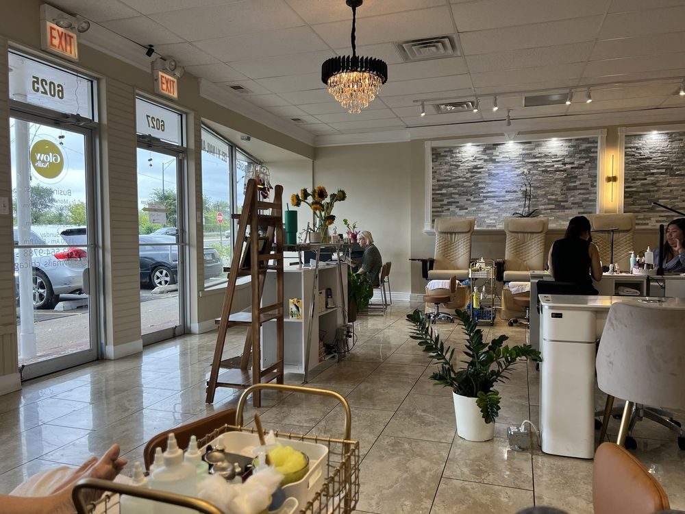 Inside Glow Nails salon: bright pedicure chairs, manicure tables and the Glow Nails logo on the door